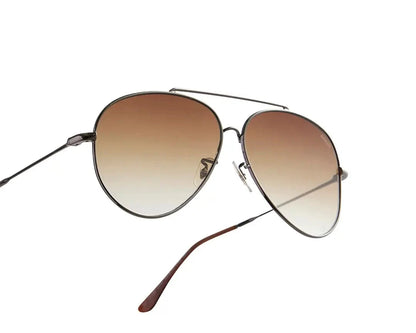 Aviator-style sunglasses with a sleek metal frame and gradient brown lenses. The design features a double bridge and thin arms with brown-tipped earpieces, giving them a classic and timeless look. The lenses transition smoothly from dark to light, adding a stylish flair while providing sun protection.