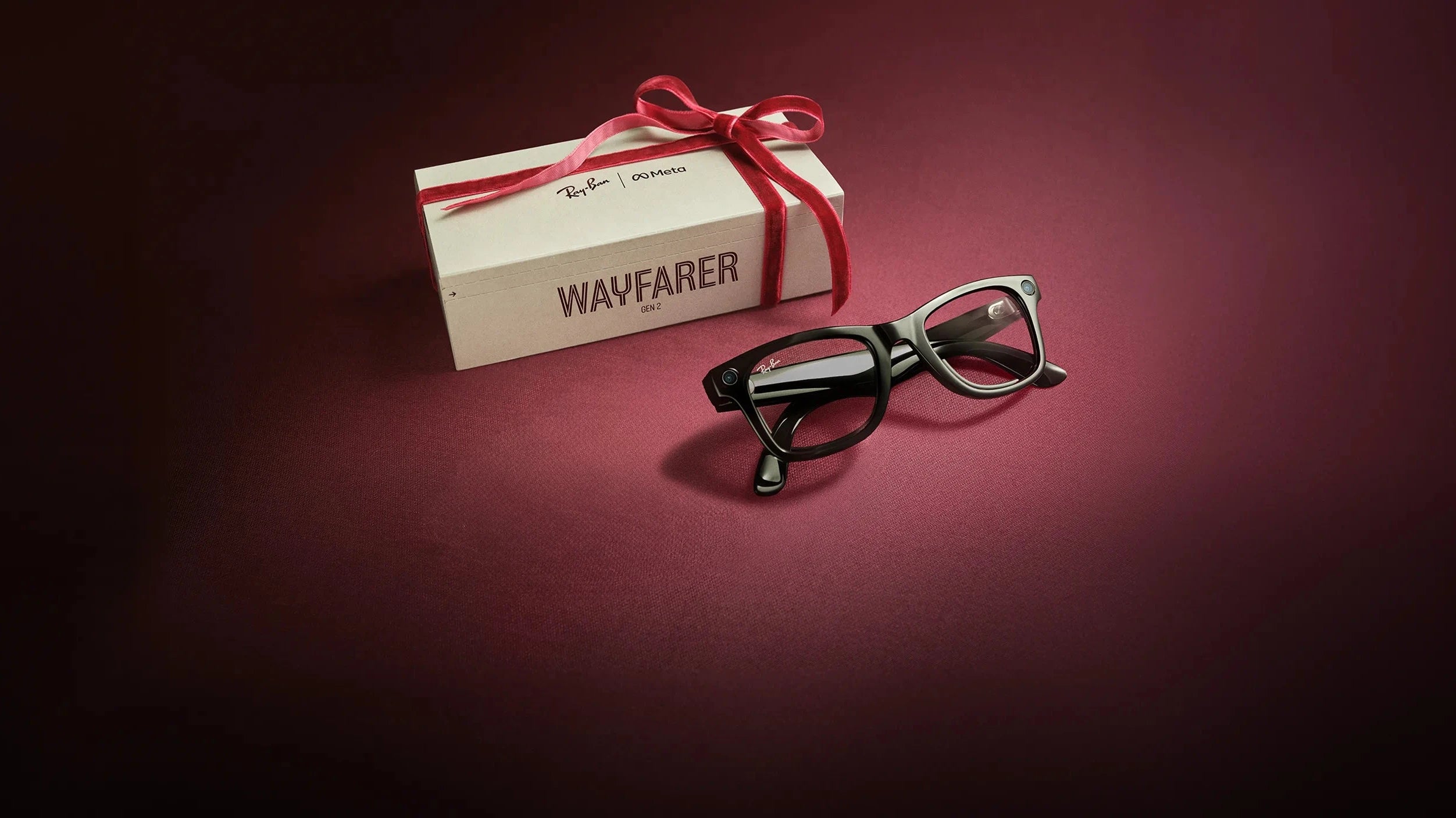 Ray-Ban Wayfarer glasses with a branded box on a dark red background
